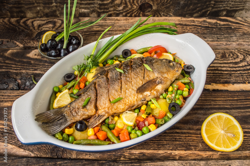 Grilled fish on brown plate with herbs and lemon old wooden background, top view. Mediterranean luxurious seafood concept. Grilled fish on brown plate with herbs and lemon old wooden background, top view. Mediterranean luxurious seafood concept.
