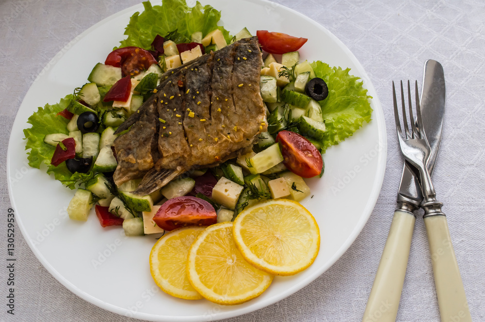 Fried fish fillet on a bed of Caesar salad. Wooden background. Top view. Fried fish fillet on a bed of Caesar salad. Wooden background. Top view.