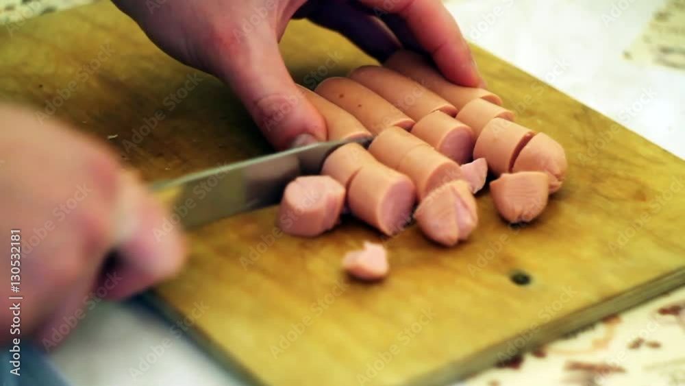 the young man cuts some sausages on the Board the young man cuts some sausages on the Board