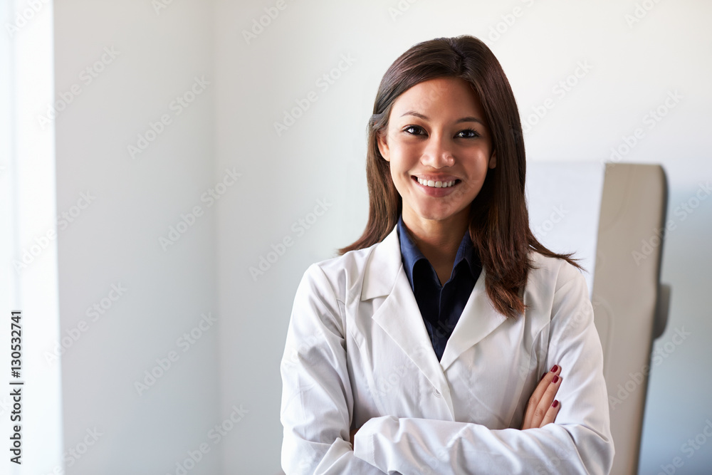 Portrait Of Female Doctor Wearing White Coat In Exam Room Portrait Of Female Doctor Wearing White Coat In Exam Room