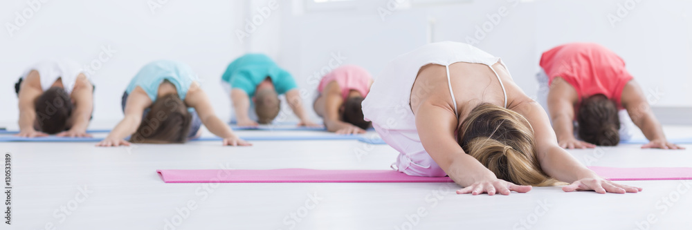 Young people stretching in a gym - obrazy, fototapety, plakaty 