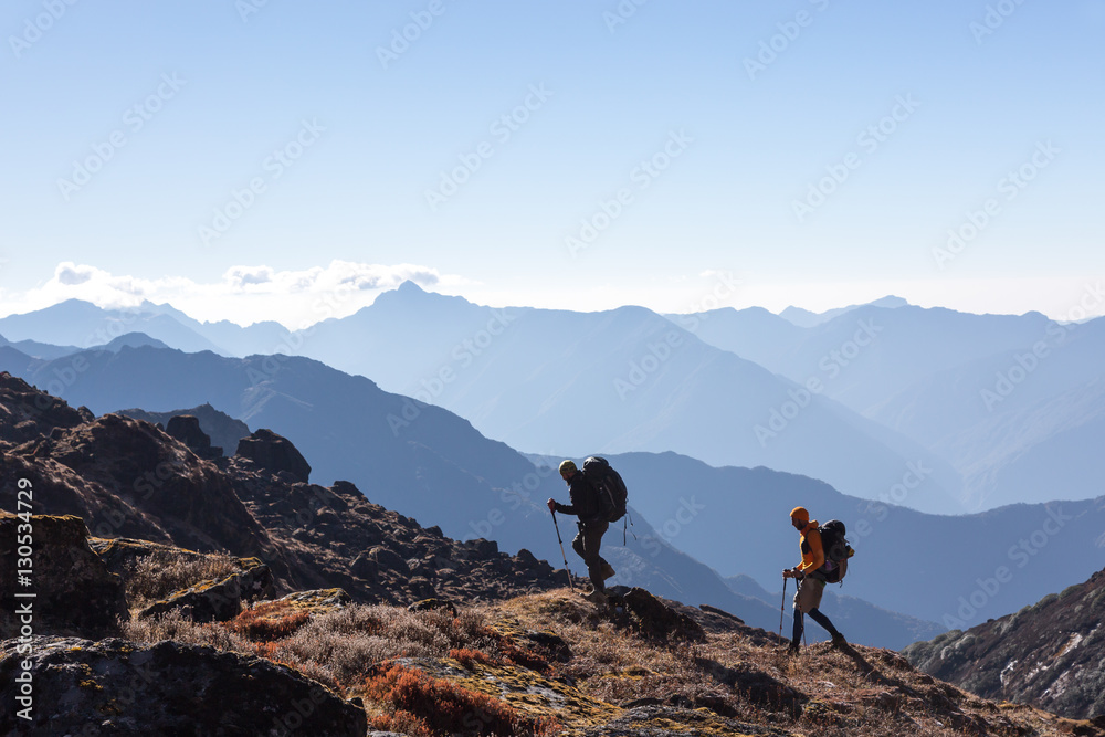 People with Backpacks and trekking Sticks traveling in Mountains