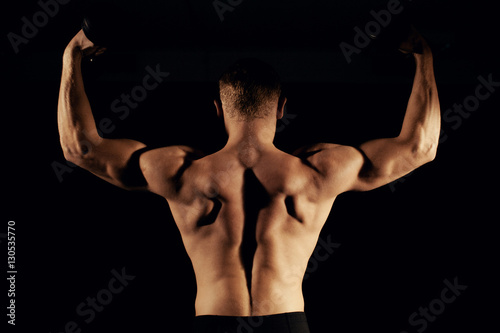 Muscular man with a dumbbell dark background