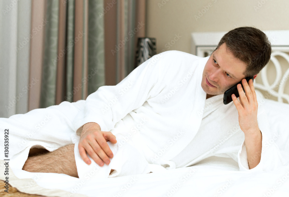 Man in bathrobe using mobile phone in hotel room. Man in bathrobe using mobile phone in hotel room.