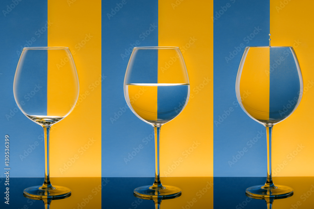Bicchieri allineati su fondo bicolore da vuoto a pieno con goccia di acqua  Stock Photo | Adobe Stock