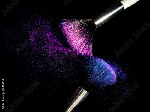 Pennelli trucco che si spazzolano creando effetto polvere colorata photo