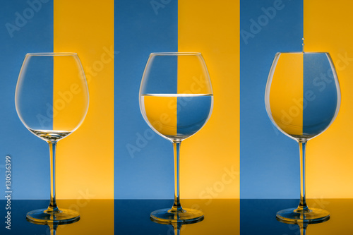 Schilderij op canvas Bicchieri allineati su fondo bicolore da vuoto a pieno con goccia di acqua