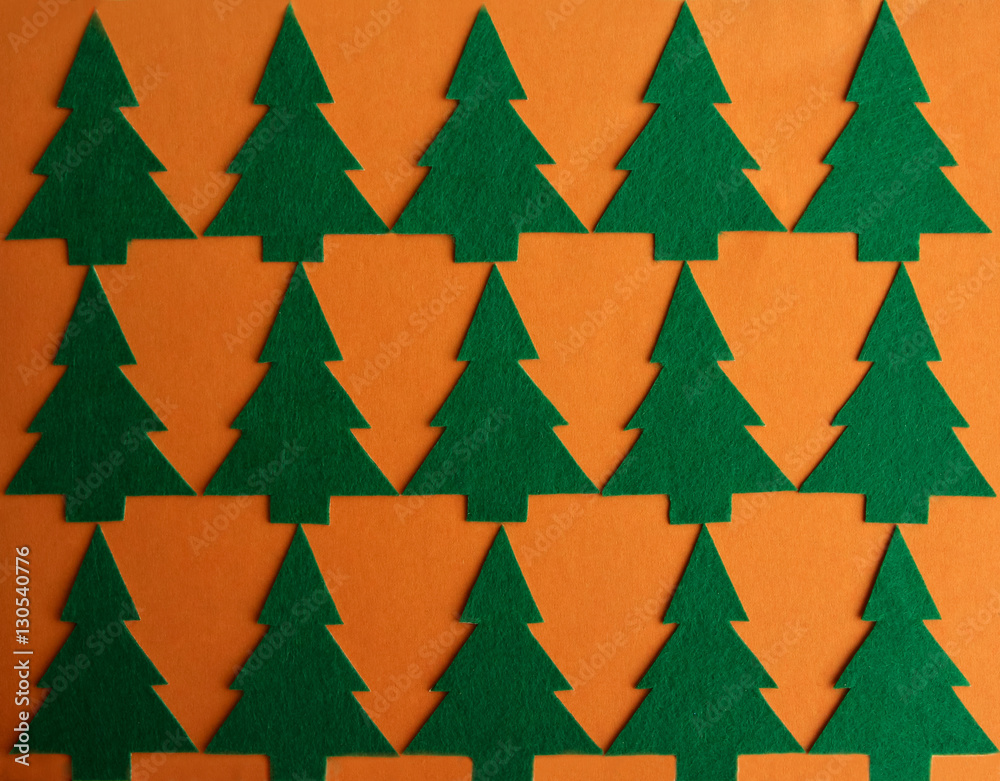 Christmas pattern with green felt christmas trees on orange back Christmas pattern with green felt christmas trees on orange back