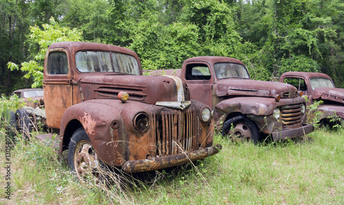 Rusting vintage trucks in a field.