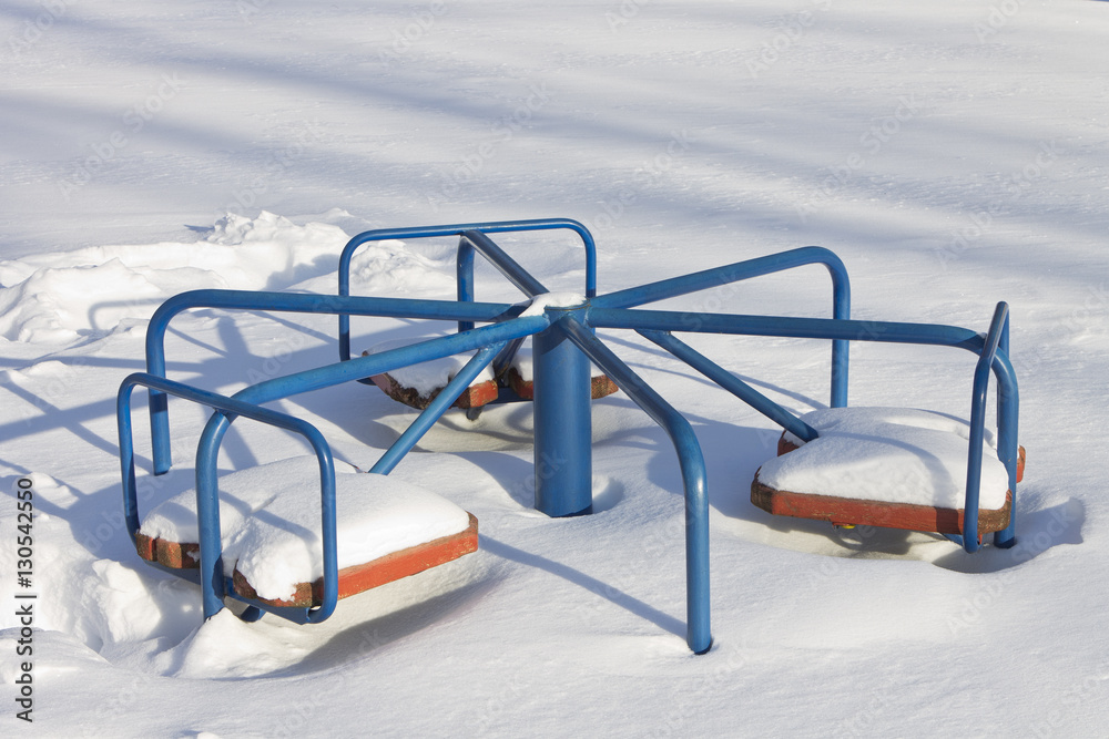 Children's carousel which is buried in the snow in a winter sunn Children's carousel which is buried in the snow in a winter sunn