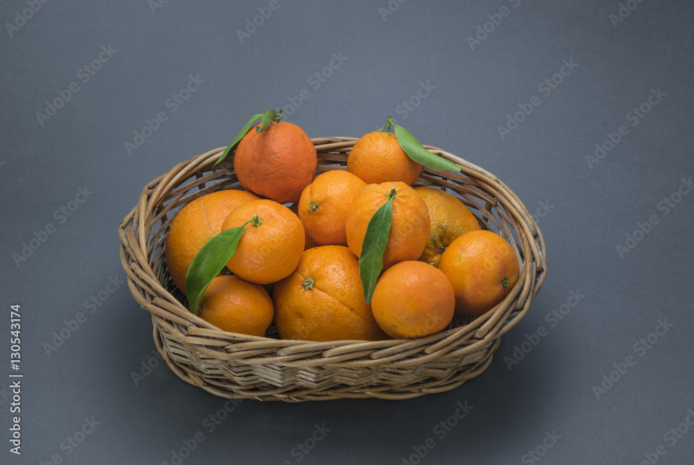 Oranges and mandarins with basket on blue background