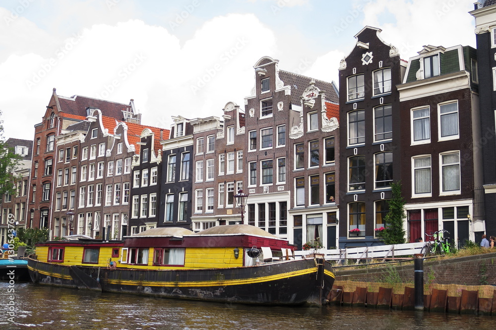 Yellow houseboat and traditionsl houses - Amsterdam - Netherlands