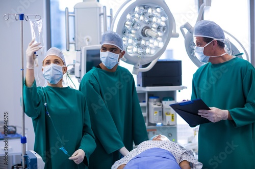 Surgeons adjusting iv drip in operation theater