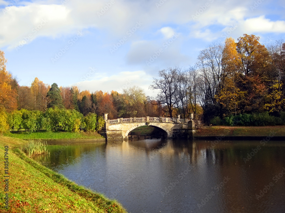 Stone bridge in old style over river in autumn countryside park Stone bridge in old style over river in autumn countryside park