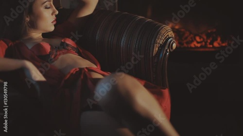 Sexy girl in red lingerie on a chair near the fireplace