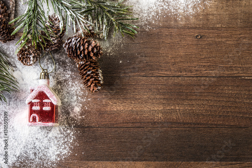 snowy cones and red house powdered with snow on a wood background