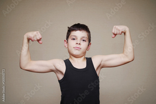 Obraz na plátně Boy is showing his arm muscles