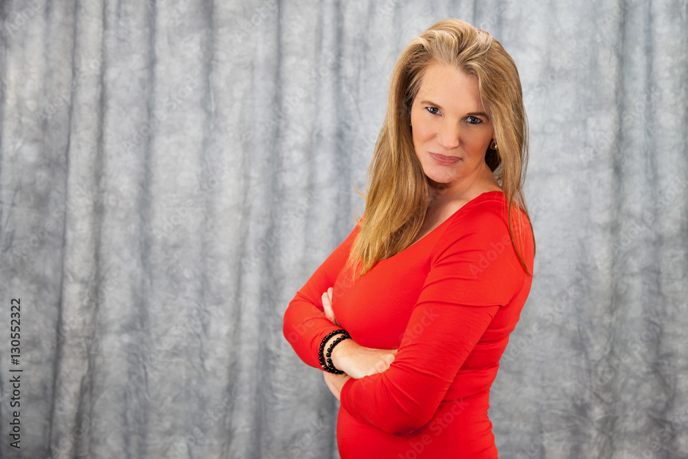 Fototapeta premium Blonde Female In Red Dress with Arms Folded Stern Look