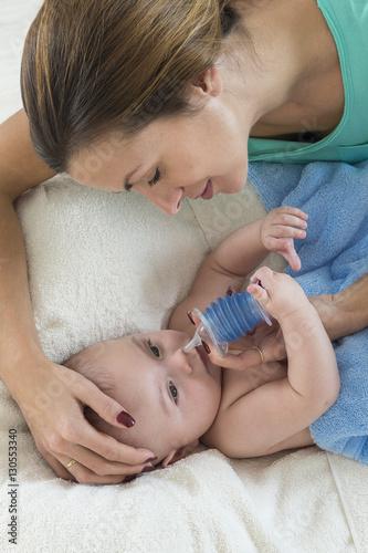 Mother cleaning baby nose with a nasal aspirator