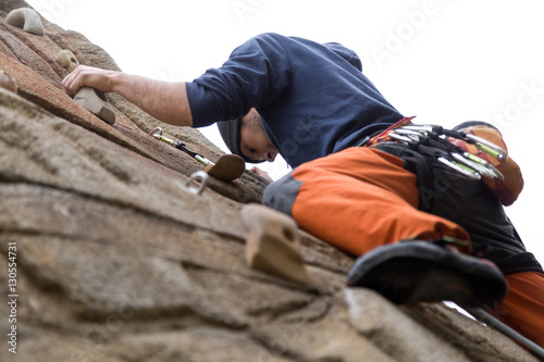 Handsome young man climbing natural rocky wall.