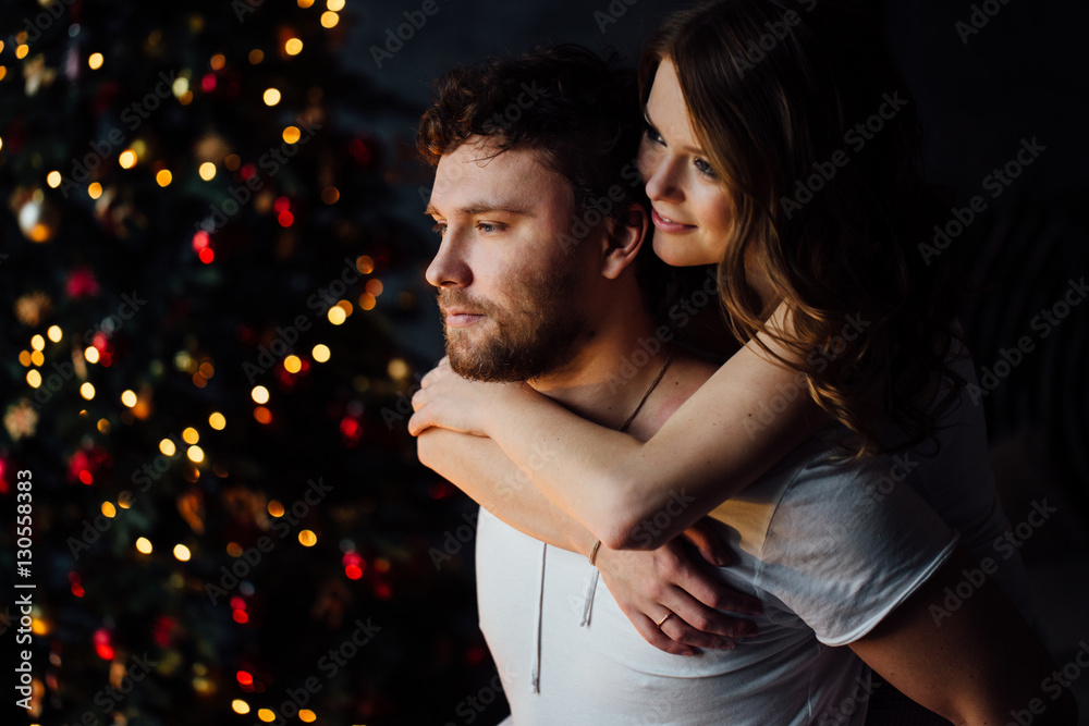Beautiful young couple in pajamas on nicely decorated Christmas tree background. Beautiful young couple in pajamas on nicely decorated Christmas tree background.