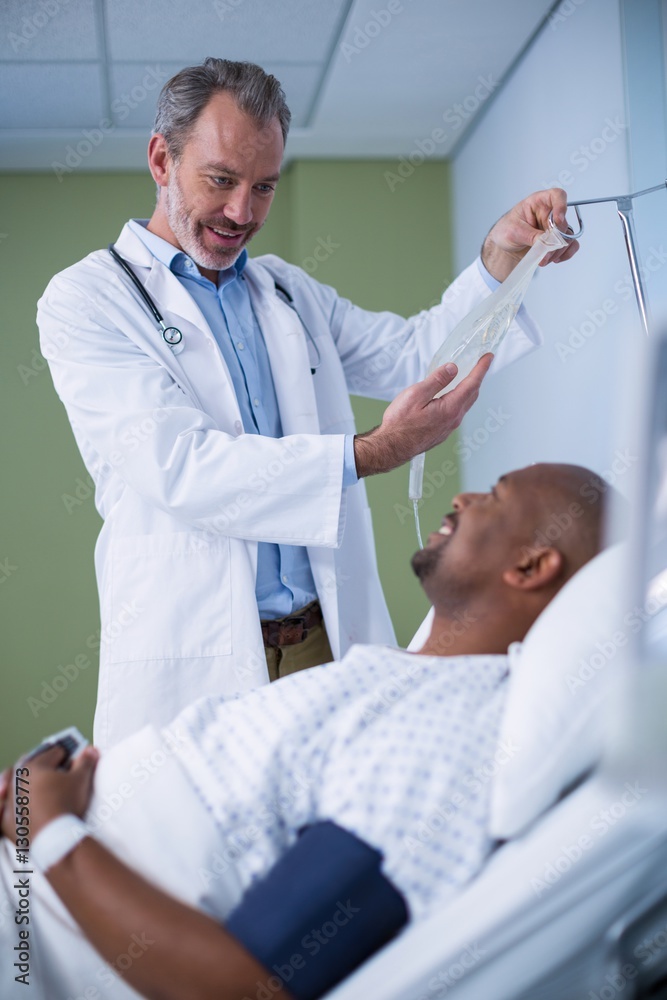Fototapeta premium Doctor interacting with patient while adjusting iv drip