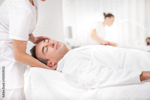Skillful masseuse massaging male head