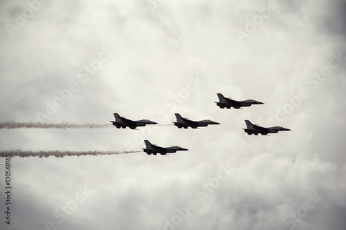 Low angle view of fighter planes in cloudy sky during airshow photo