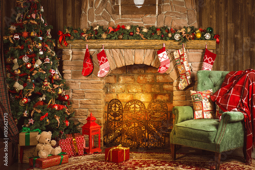 Christmas room with fireplace, an armchair and a Christmas tree with gifts Fototapeta