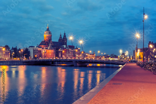 Night panoramic city view of Amsterdam canal  bridge and Basilica of Saint Nicholas  Holland  Netherlands. Long exposure.