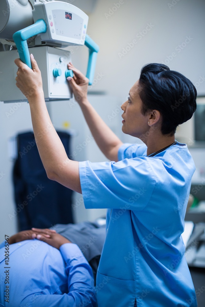 © WavebreakMediaMicro - Female doctor sets up the machine to x-ray over patient © WavebreakMediaMicro - Female doctor sets up the machine to x-ray over patient