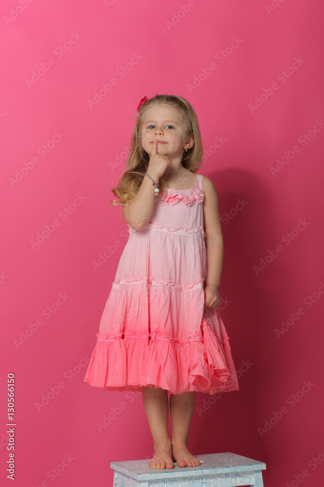 Child showing silence symbol. Pink background