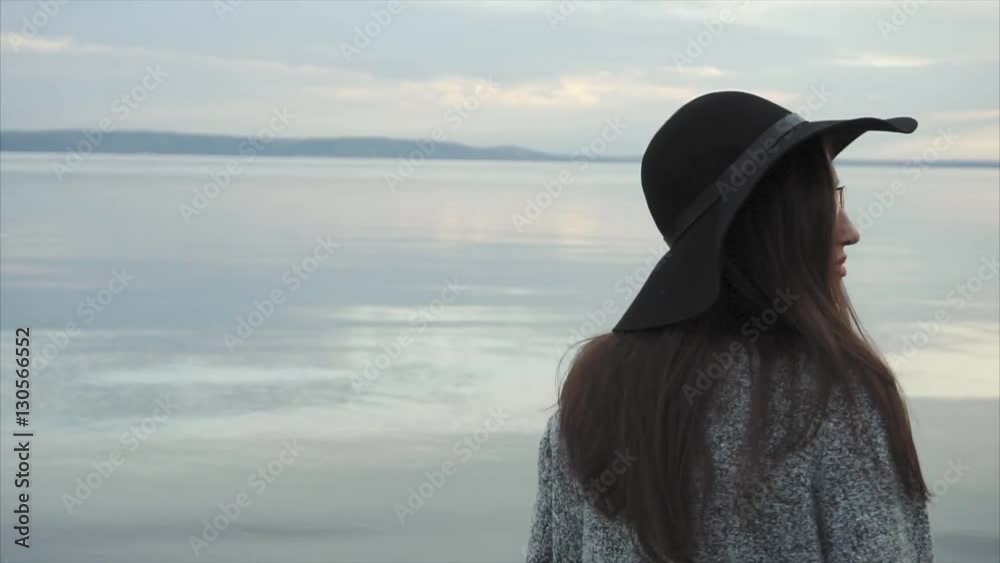 Young woman in black hat and glasses near the sea at sunset HD Young woman in black hat and glasses near the sea at sunset HD