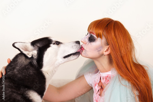 Dog Siberian Husky kisses on the lips red-haired girl in a zombi