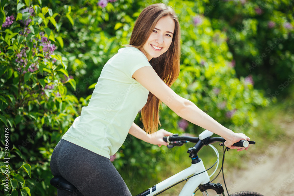 Fototapeta premium Happy young girl cyclist standing with a mountain bike and. Adventure travel. Girl cyclist. Mountain bike. healthy lifestyle. Sort concept.