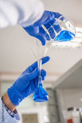 Laboratory technician performs tests and pouring blue liquid