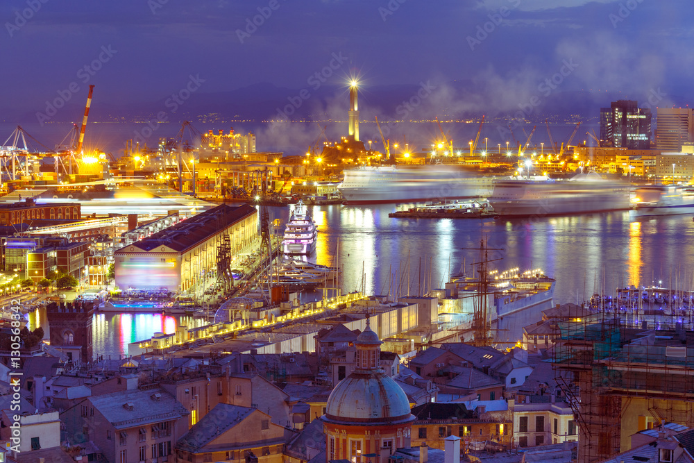 Historical Lanterna old Lighthouse, container and passenger terminals in seaport of Genoa on Mediterranean Sea, at night, Italy.