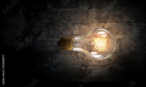 Light bulb on brick surface . Mixed media
