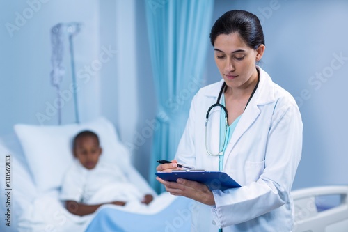 Female doctor writing on clipboard in hospital
