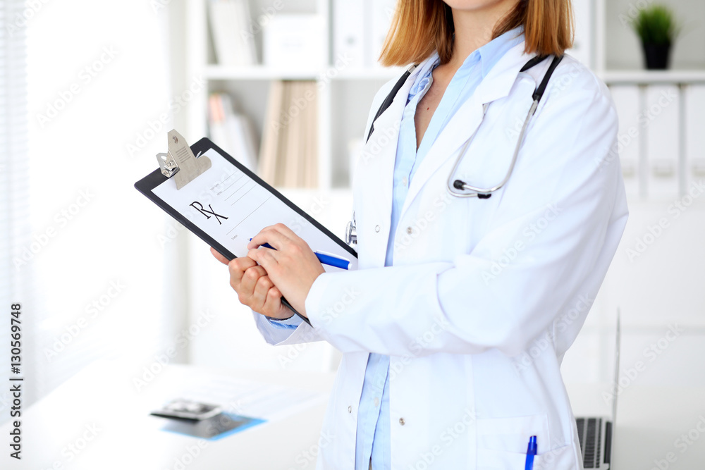 Close up of female doctor writing a medical prescription at clipboard while standing Close up of female doctor writing a medical prescription at clipboard while standing