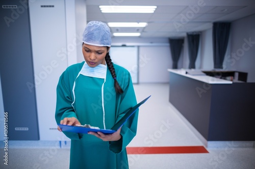 Surgeon checking report in corridor