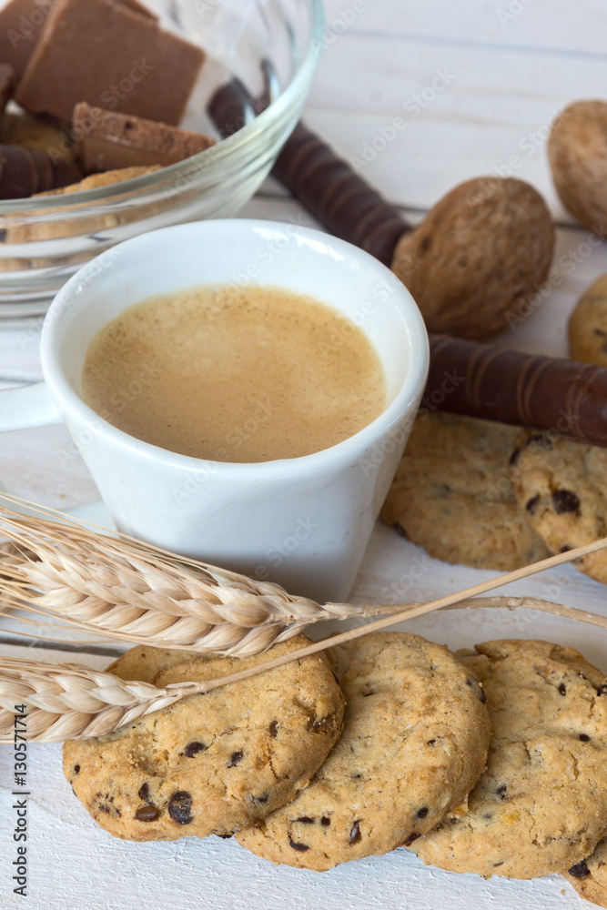 Cup of coffee, cookies, walnut and chocolate on the white wooden background
