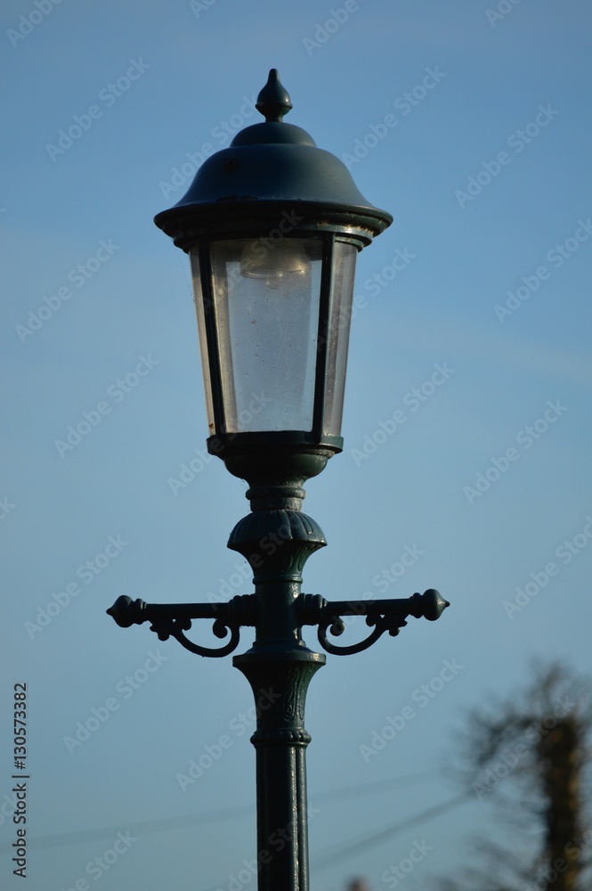 Head of an old fashioned victorian style lampost against a blue sky