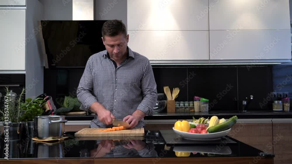 Young man cutting carrots, smiles to camera. Slider shot.
Young man cutting carrots, smiles to camera. Slider shot.