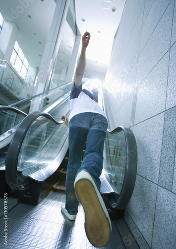 Young man running up escalator