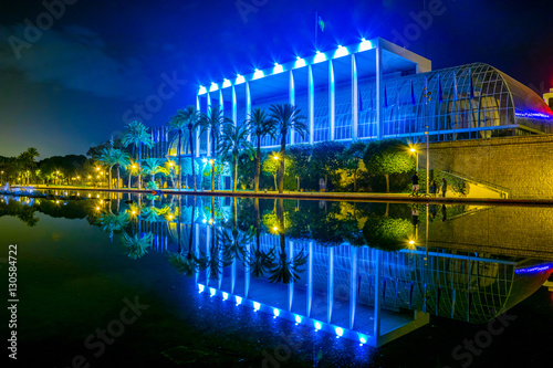 View of the palau de la musica de valencia concert hall reflecting in a pond during night.