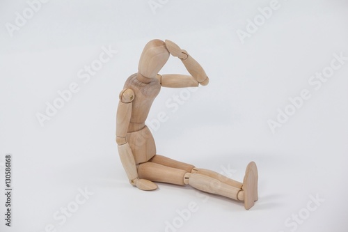 Tensed wooden figurine sitting with hand on head