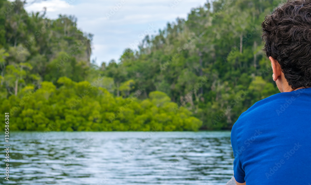 Fototapeta premium Traveler looking into Mangrove Jungle near Warikaf Homestay, Kabui Bay and Passage. Gam Island, West Papuan, Raja Ampat, Indonesia