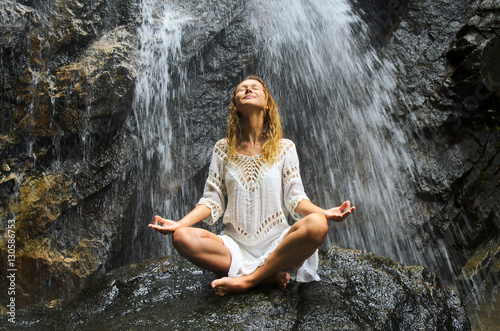 Female Practising Yoga on Waterfall. Stock image.