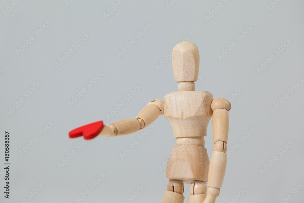 Wooden figurine standing and giving a red heart Wooden figurine standing and giving a red heart
